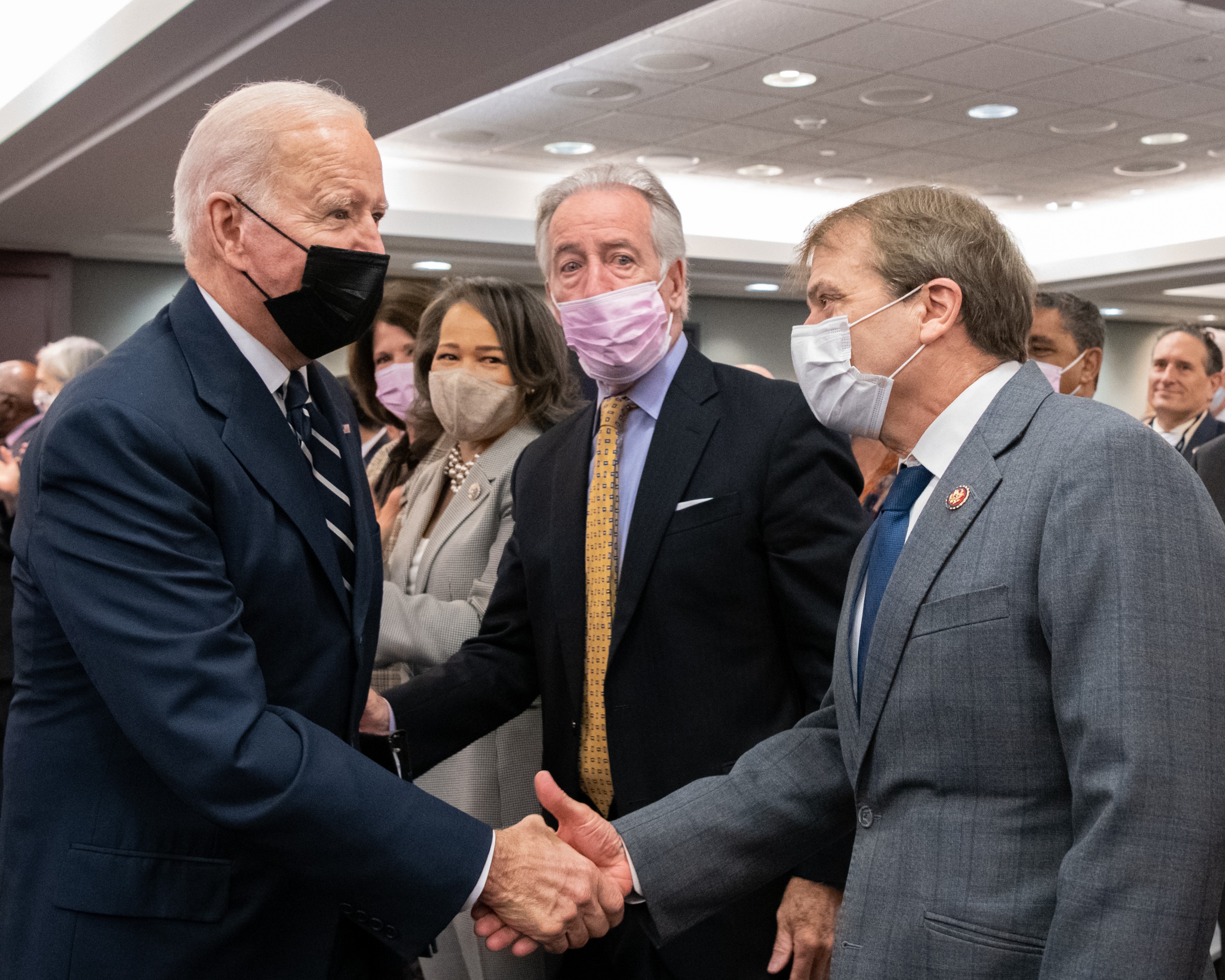 president joe biden and congressman mike quigley shake hands in a crowded room