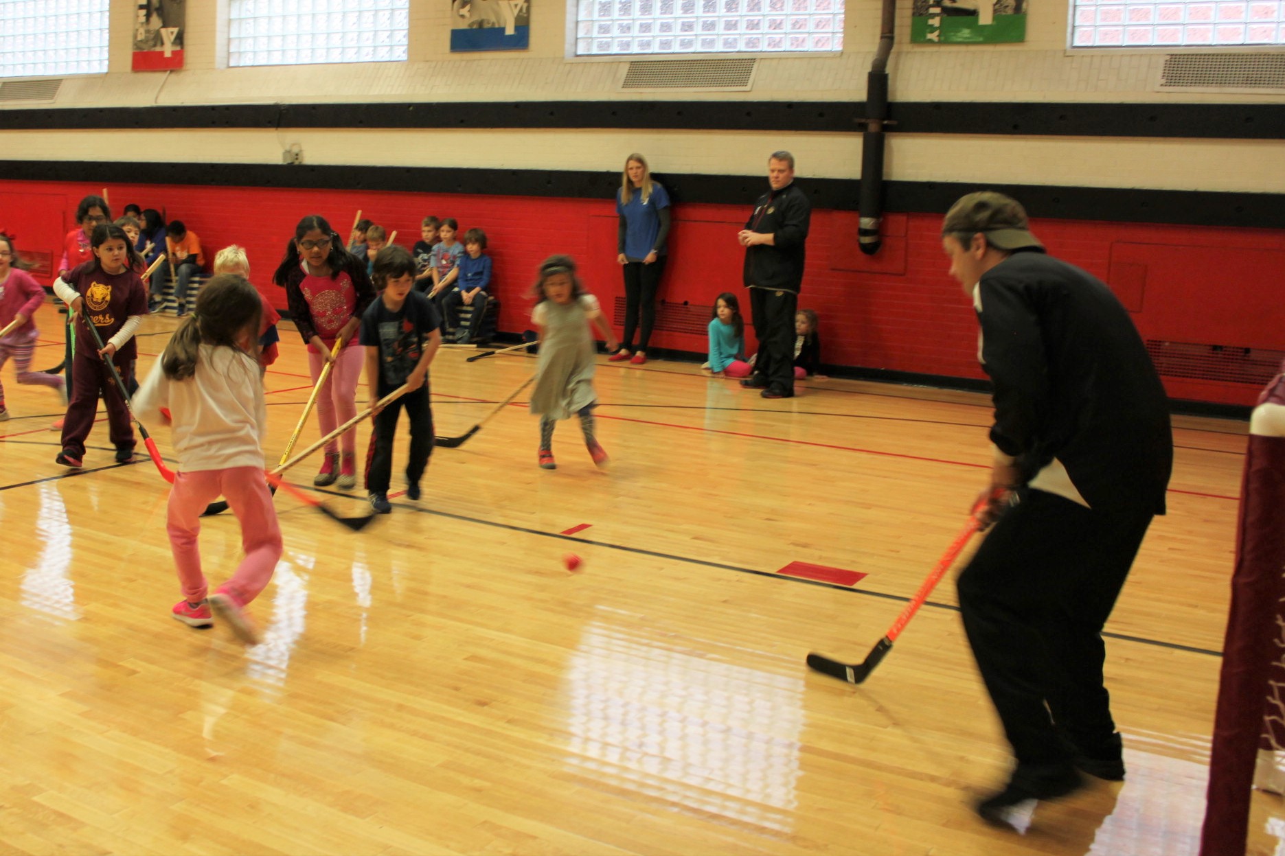 Rep Quigley plays hockey with a group of children in a YMCA gym