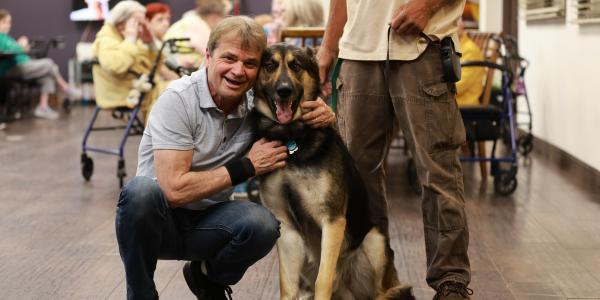 Rep. Mike Quigley kneels on the ground to pose for a photo with a german shepherd