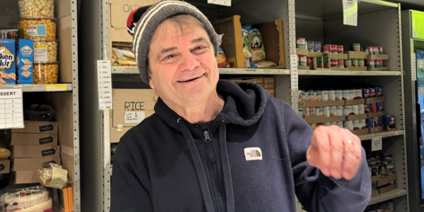 Rep. Quigley smiles in front of a shelf of nonperishable foods as he packs a grocery bag with foods.