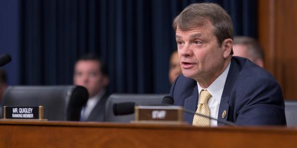 Quigley sits at a dias in a Congressional room behind a nameplate that says Mike Quigley Ranking Member