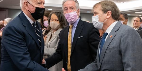 president joe biden and congressman mike quigley shake hands in a crowded room