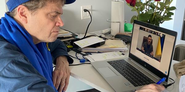 Mike Quigley sits at a computer that displays a video call with Ukrainian President Zelensky