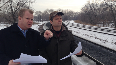 Rep Quigley holds white papers overlooking railroad tracks in the snow