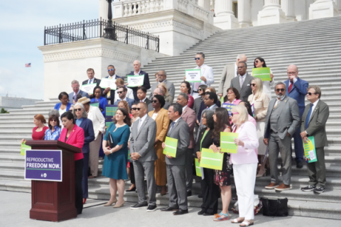 Rep. Quigley stands on the steps of the US Capitol with a few dozen of his colleagues, all in professional attire, holding bright green signs that call for reproductive freedom