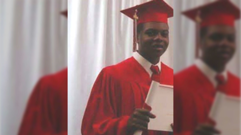 Laquan McDonald poses in a red graduation cap and gown holding a certificate