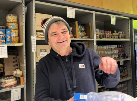 Rep. Quigley smiles in front of a shelf of nonperishable foods as he packs a grocery bag with foods.