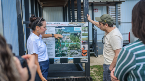 Rep Quigley stands at a large display board with a staff member who is demonstrating something using the board