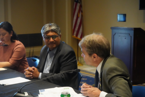 Quigley sits at a table speaking with Jigar Shah, Director of DOE’s Loan Programs Office 