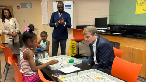 Rep Quigley sits at a table with a child looking over a game