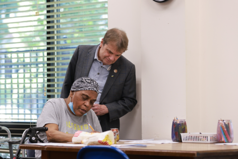 Rep Quigley looks over the shoulder of an older black woman