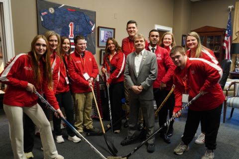 MQ in his office surrounded by special olympics athletes all holding hockey sticks