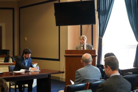 Rep Quigley speaks from a podium in a meeting room
