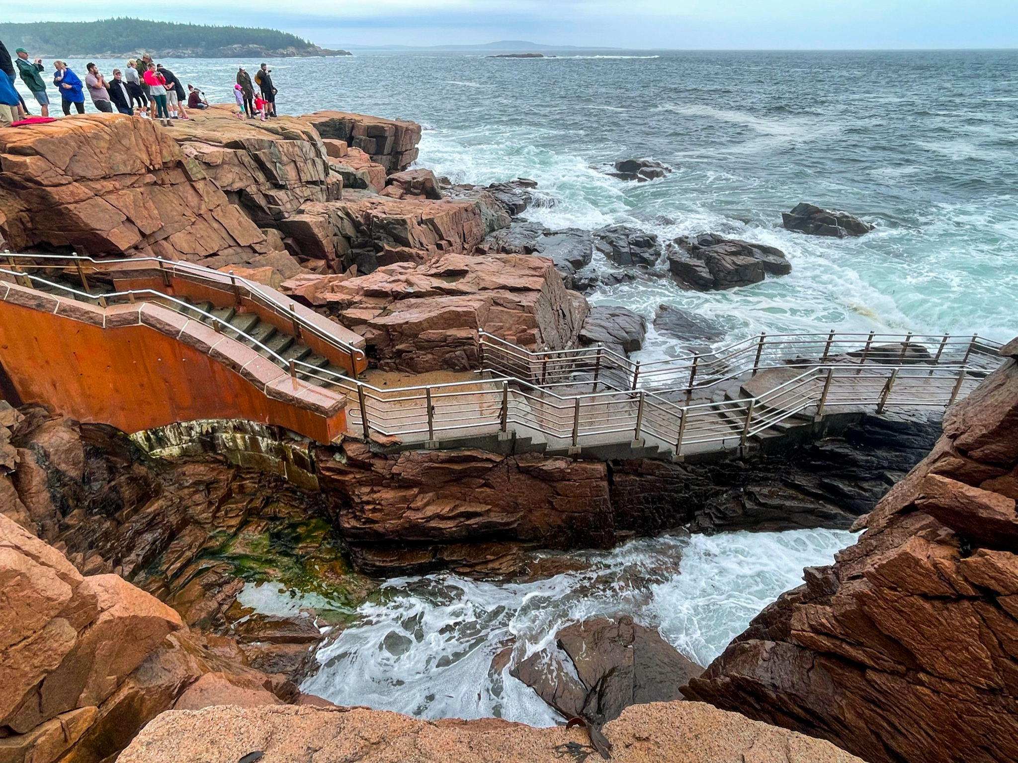 Orange-red cliffs with a group of tourists looking into the ocean